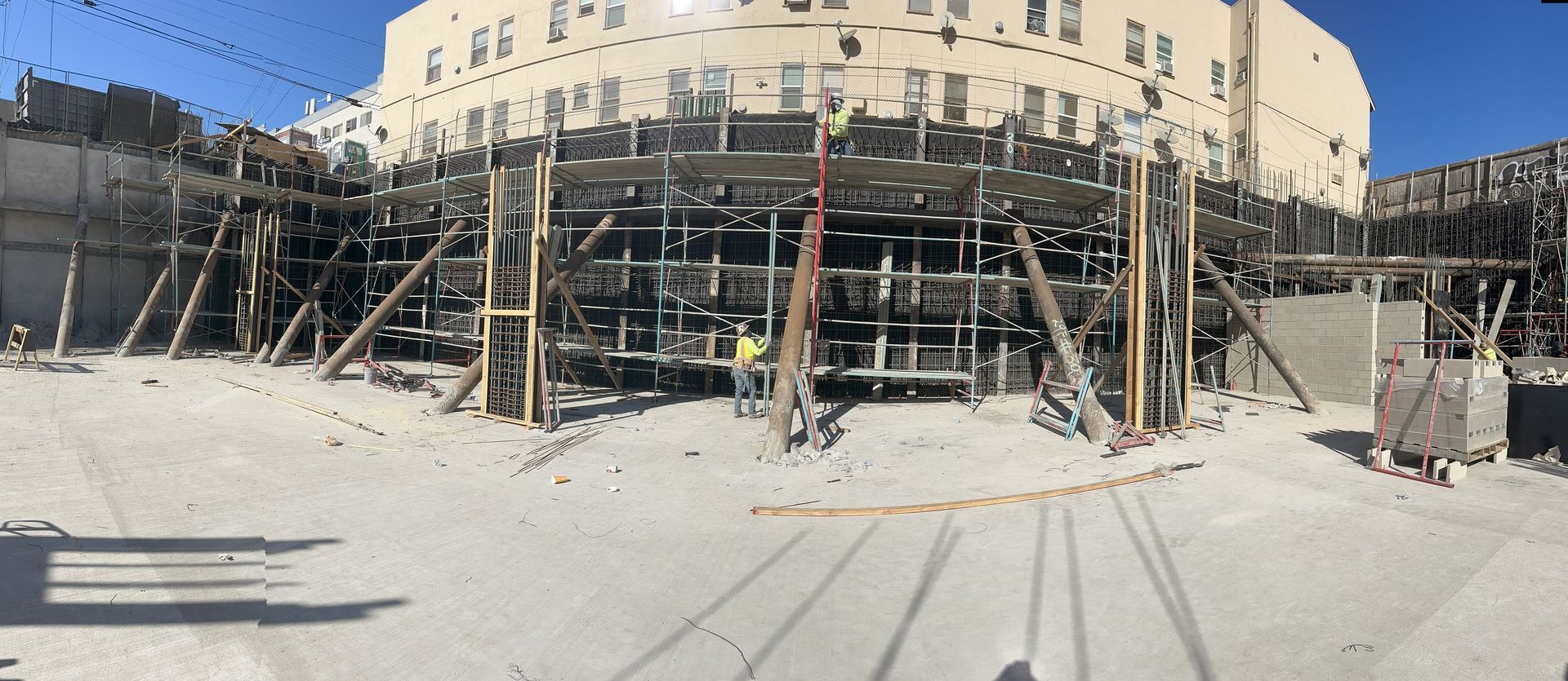 Construction site with scaffolding in front of a building. A worker stands in the middle.