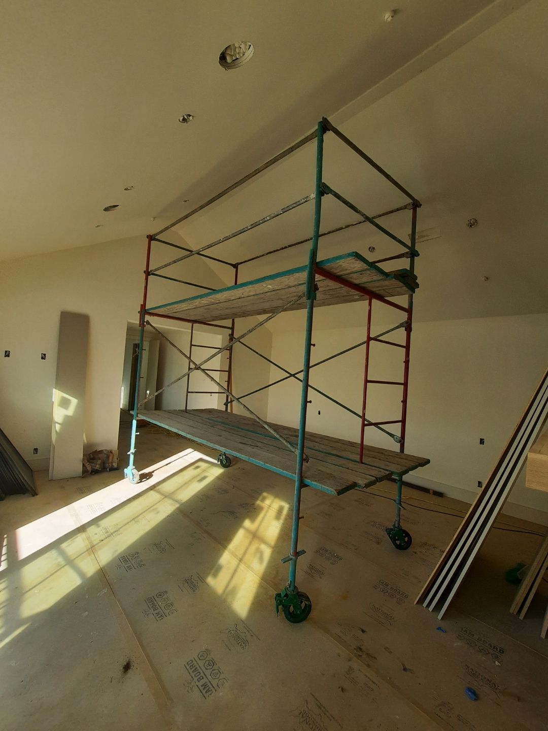 Scaffolding inside a room under construction with sunlight streaming in.