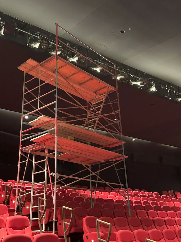 Red scaffolding inside a theater, extending towards the ceiling above red seats.