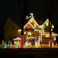 House decorated with colorful Christmas lights and glowing lawn ornaments at night