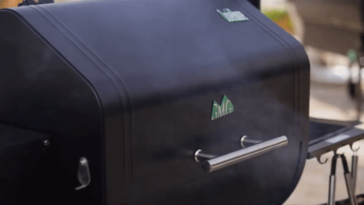 Black smoker grill with steam escaping; outdoors.
