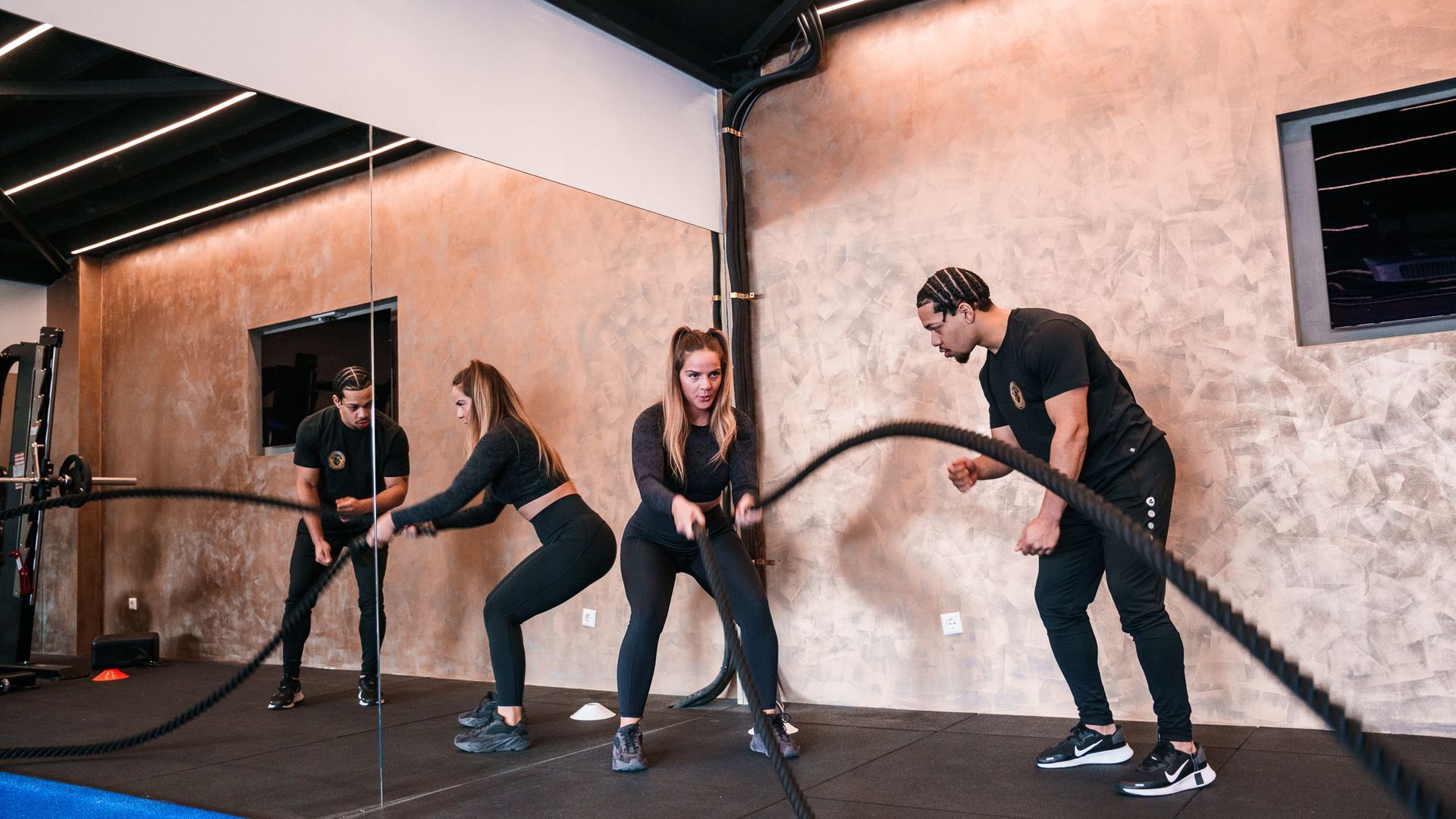 Een groep mensen doet oefeningen met touwen in een sportschool.