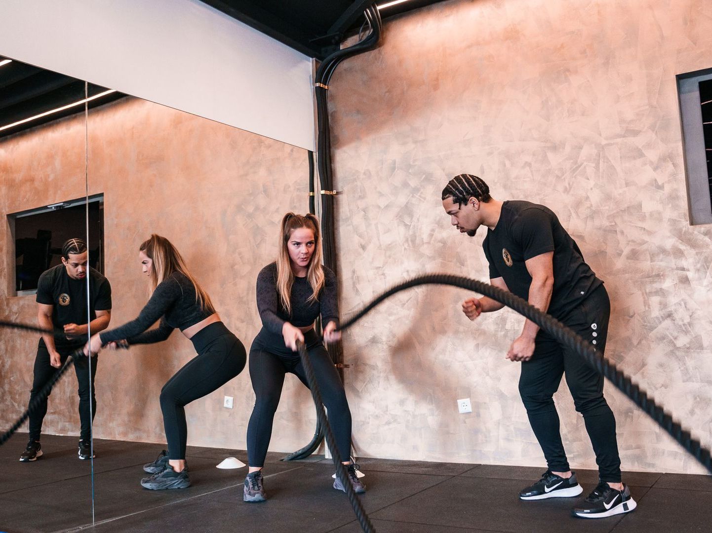 Een groep mensen doet oefeningen met touwen in een sportschool.