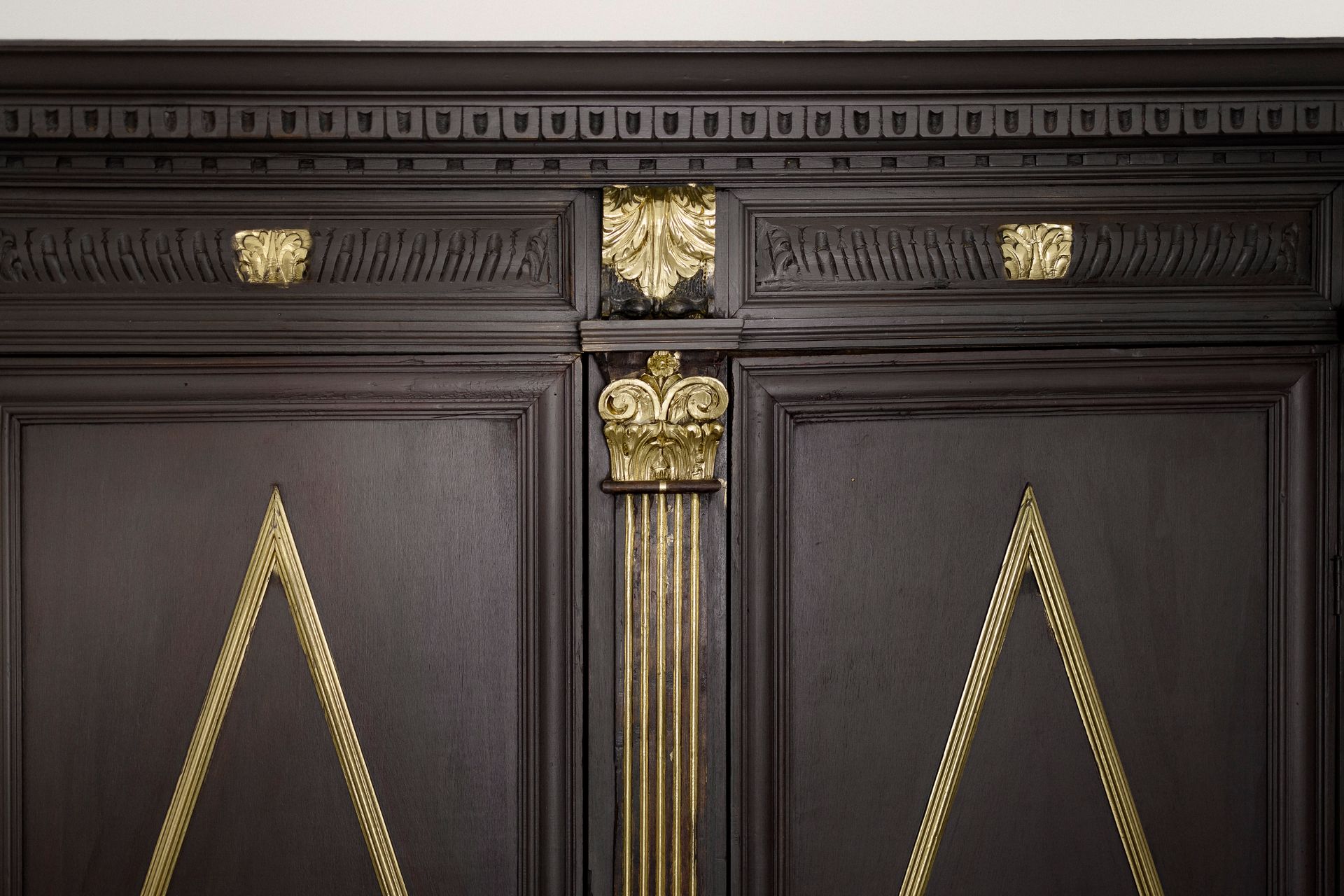 Ornate dark wood double doors with gold decorative trim and central column detail