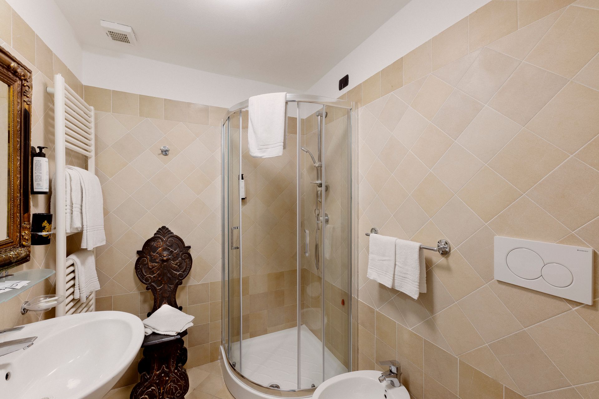 Small beige-tiled bathroom with a glass shower, sink, and toilet.