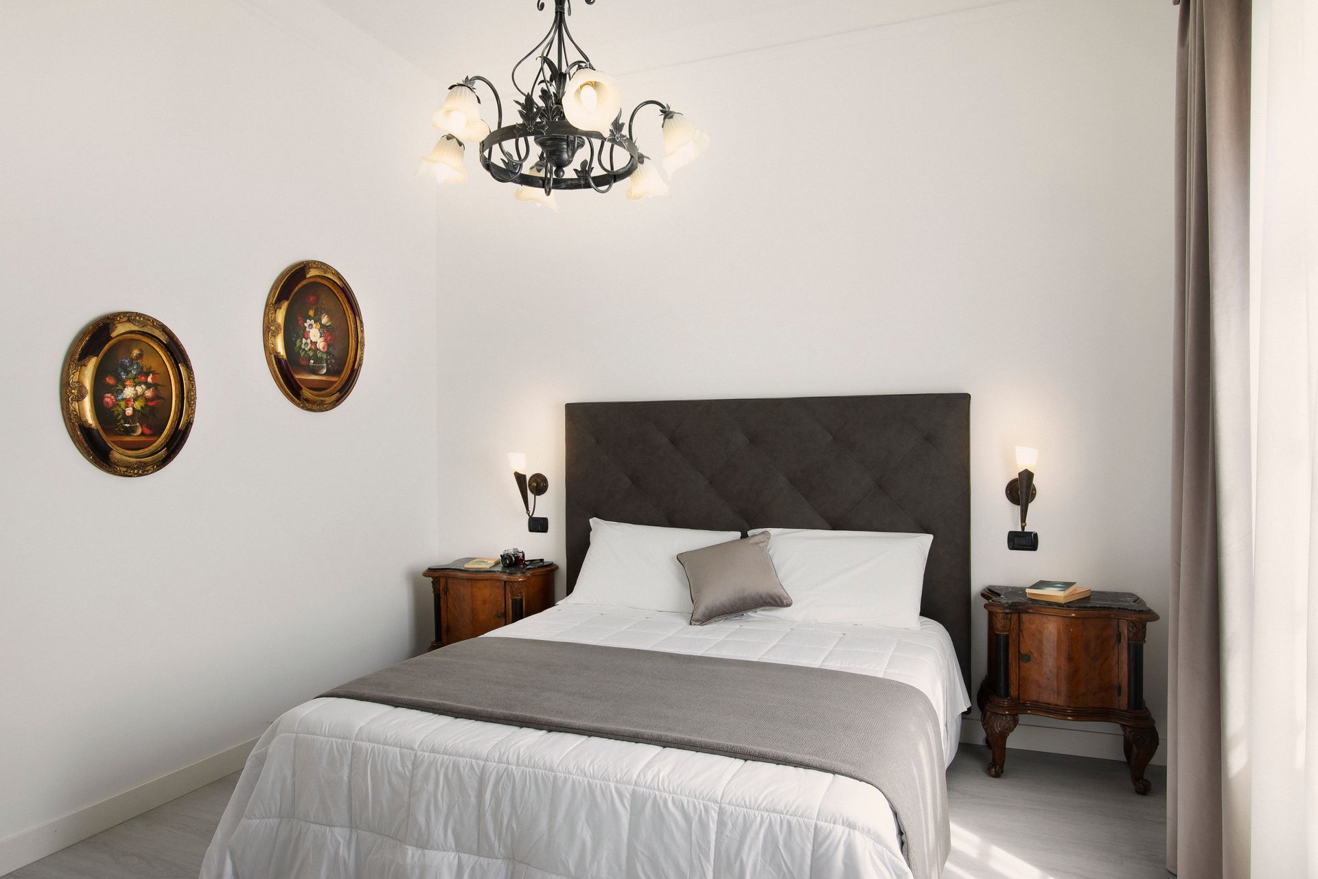 Bright bedroom with a gray bed, white bedding, dark wood nightstands, and decorative wall art