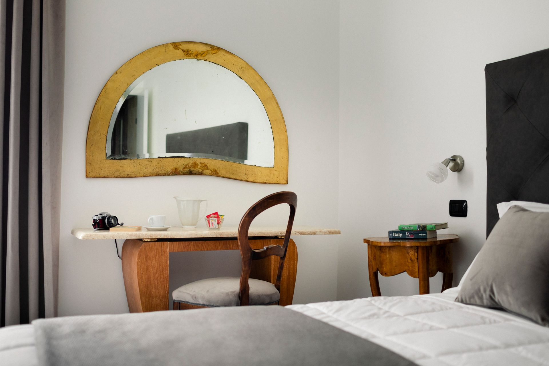 Bedroom with bed, desk, chair, and a gold-framed mirror above the desk