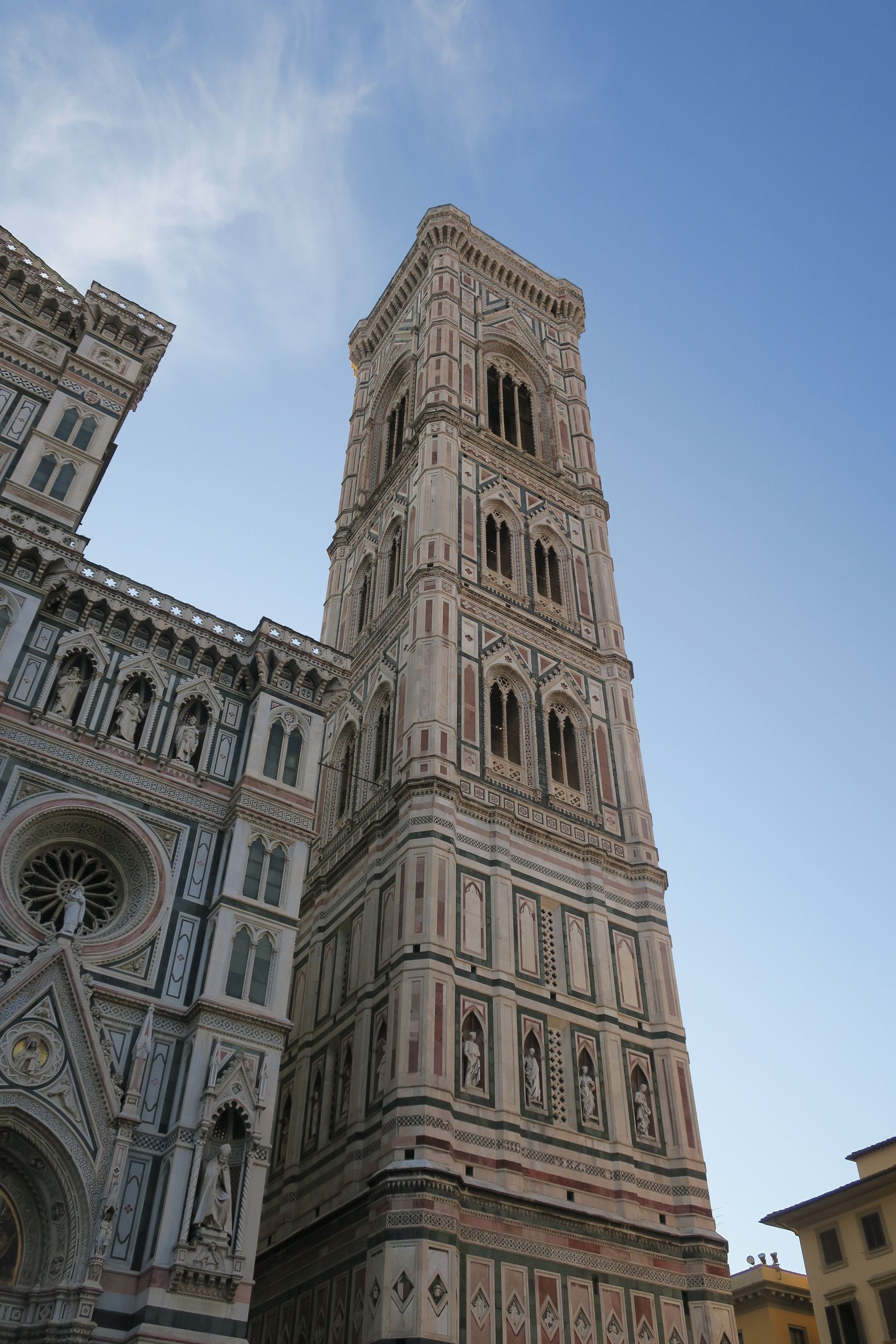 Alta y ornamentada torre de catedral junto a una fachada decorada contra un cielo azul