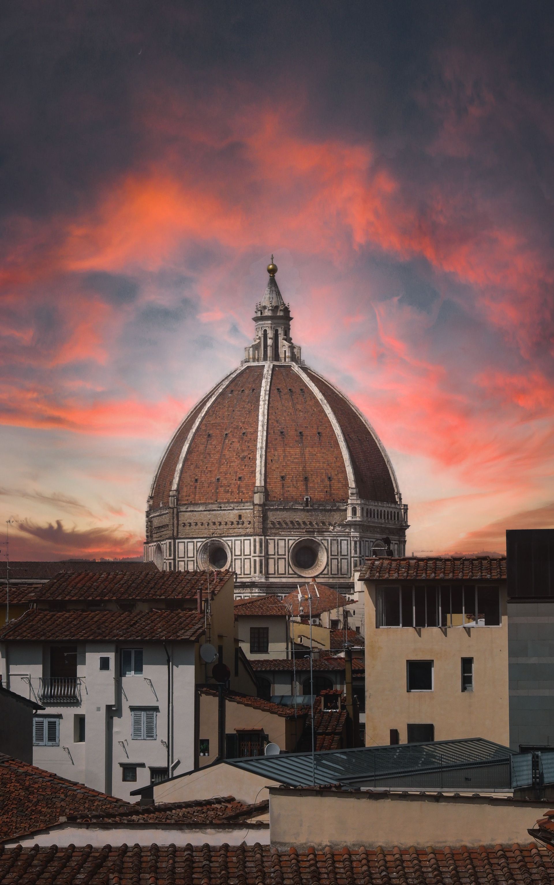 El horizonte de Florencia al atardecer con la cúpula del Duomo sobre los tejados y un cielo rosa anaranjado.