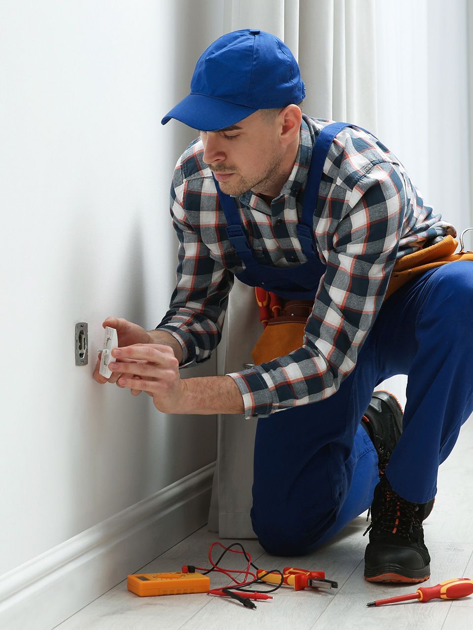 Professional male electrician repairing power socket in room