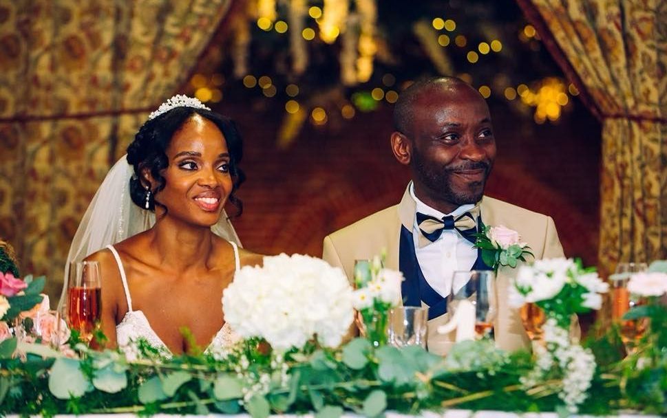 A bride and groom are sitting at a long table at their wedding reception.