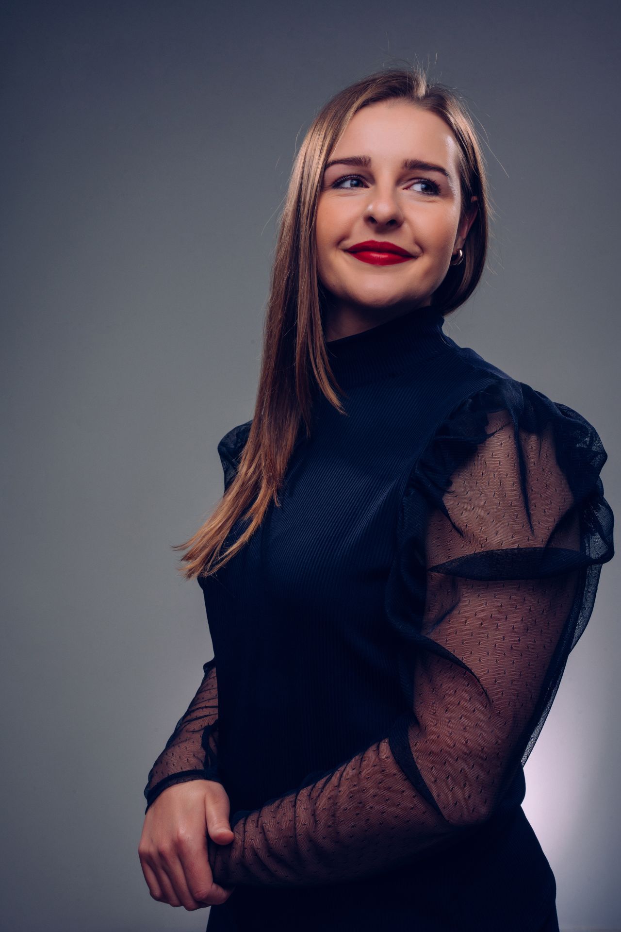 The woman is wearing a black dress and red lipstick.