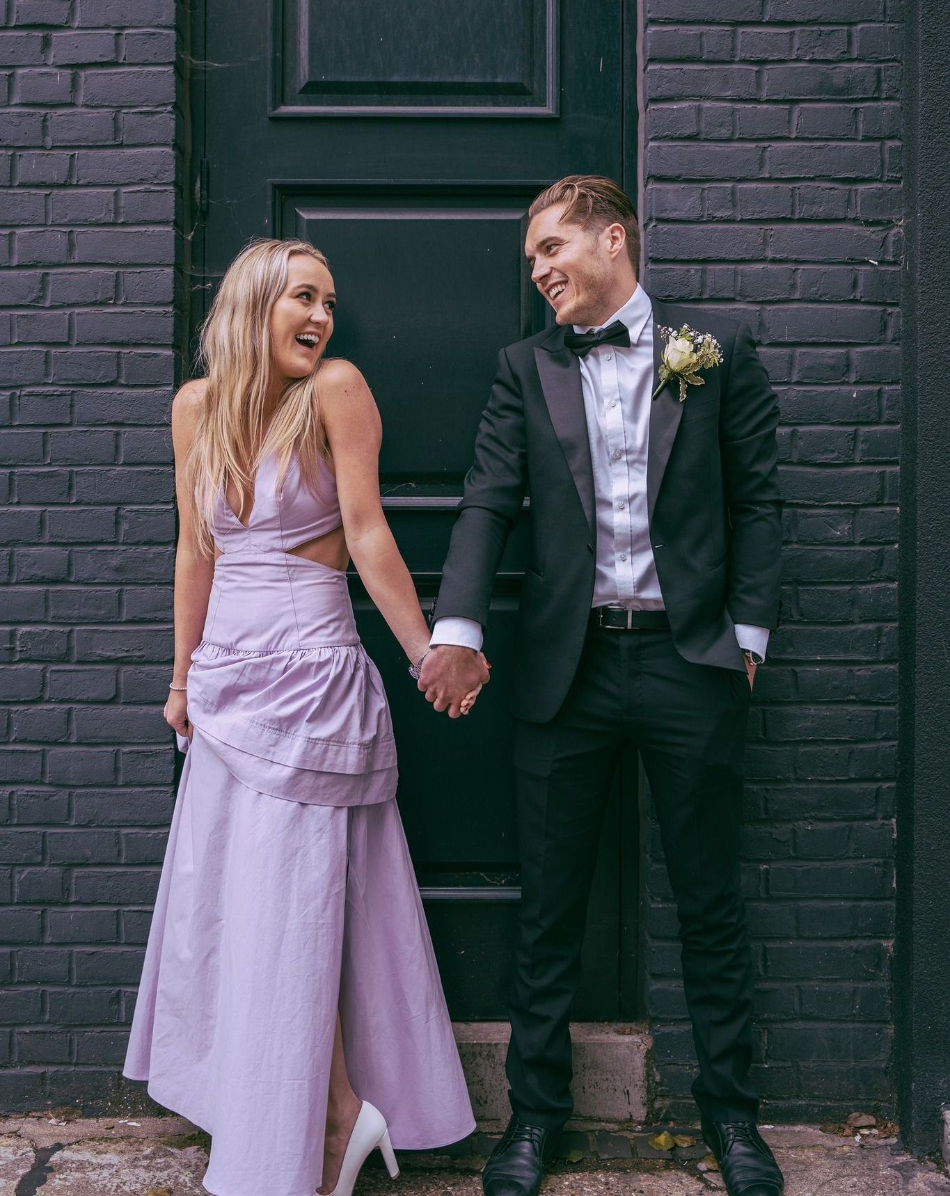 A bride and groom are holding hands in front of a black door.