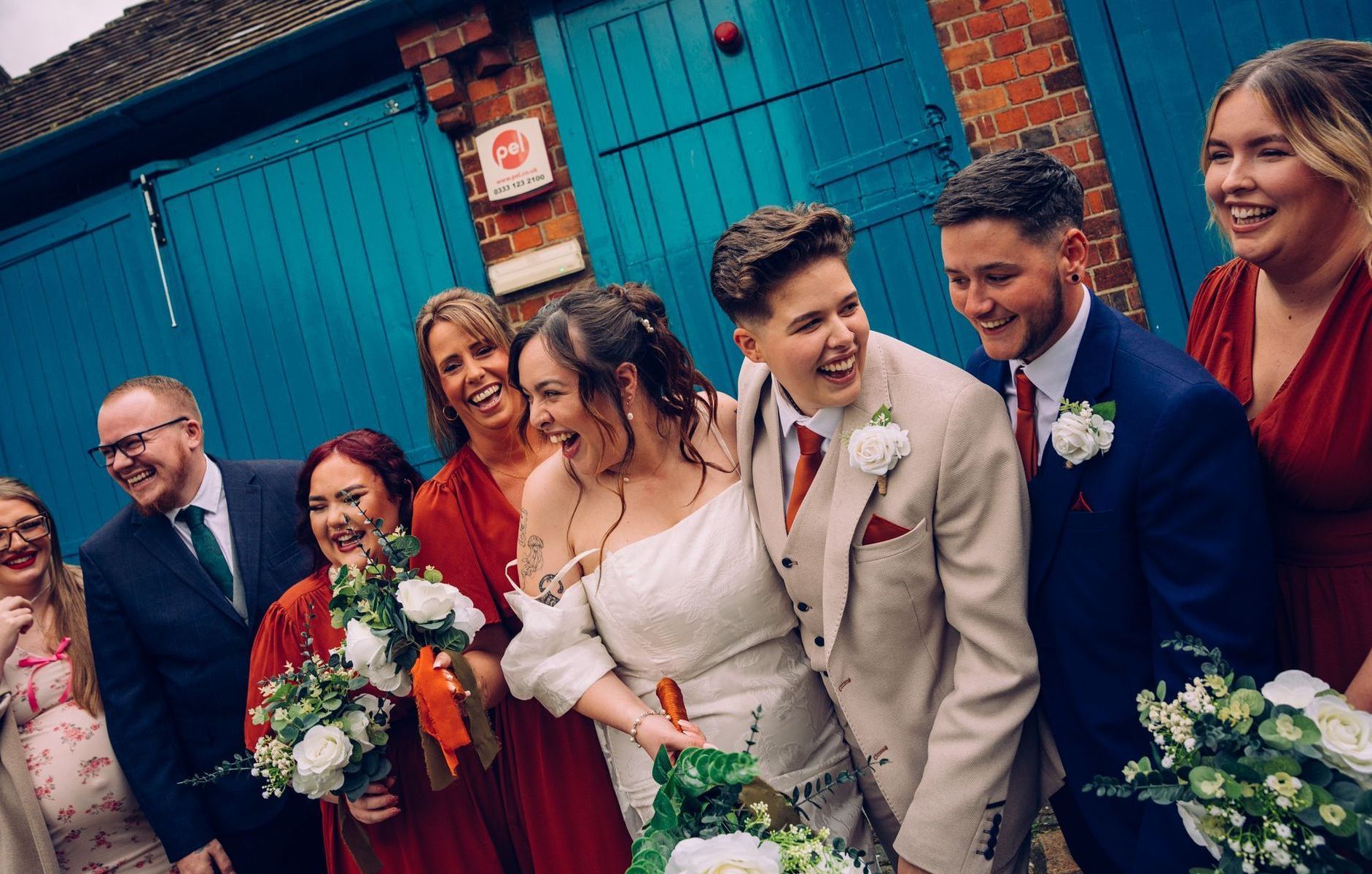 A married couple are posing for a picture with their wedding party.