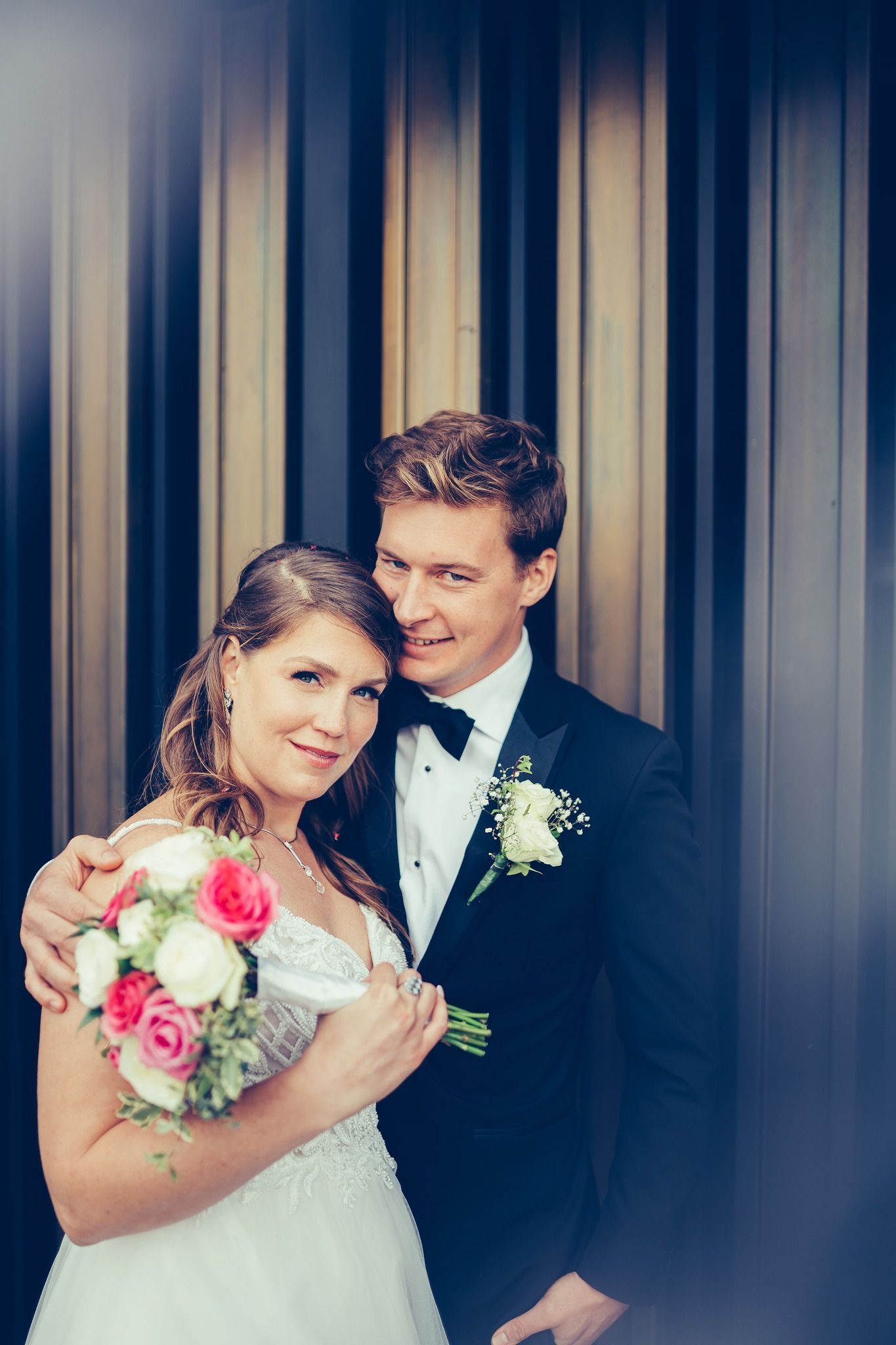 A bride and groom are posing for a picture in front of a building.