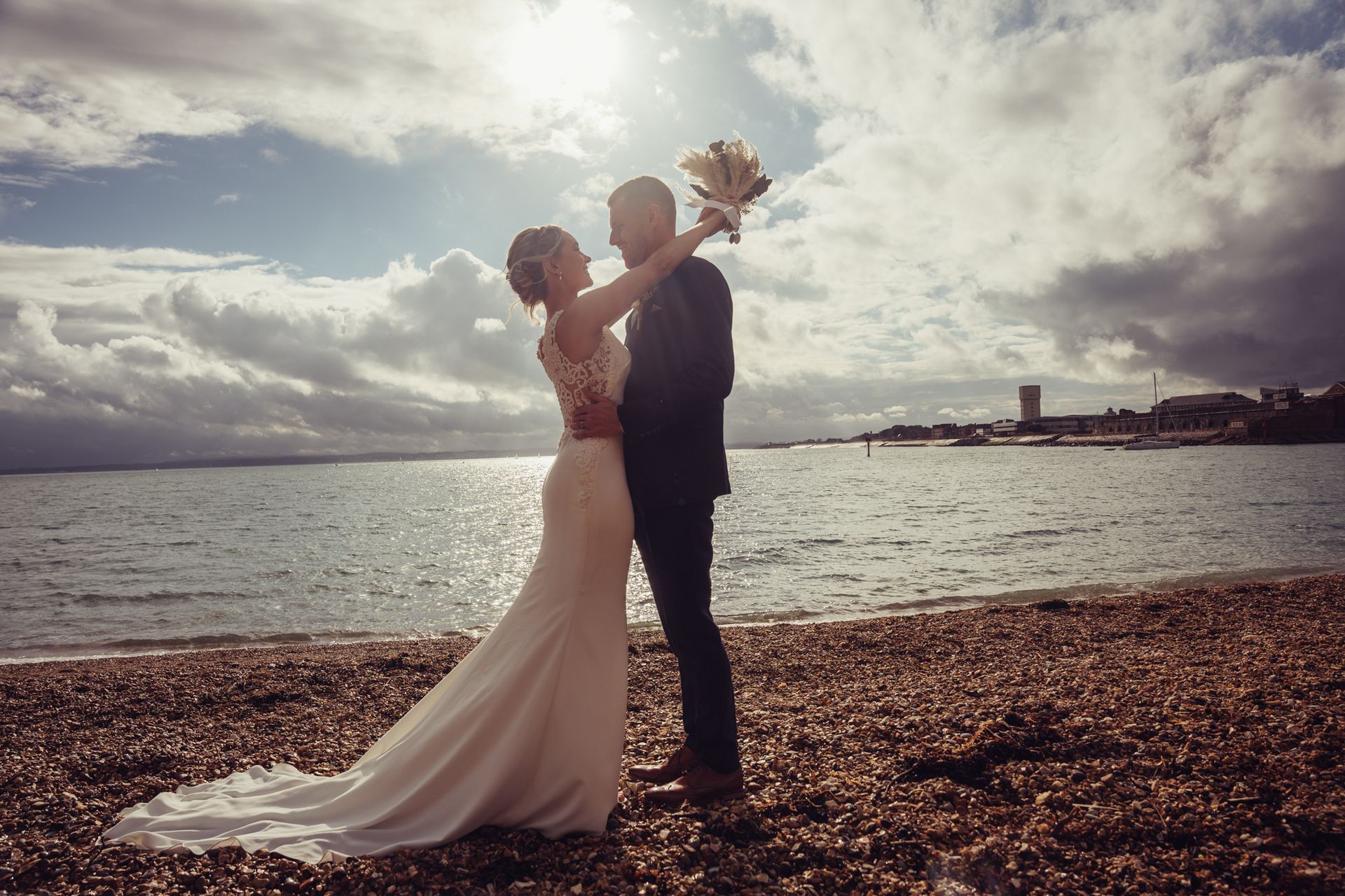 A bride and groom are posing for a picture on the beach