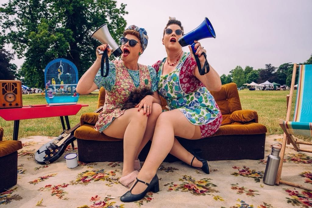 Two women are sitting on a couch holding megaphones.