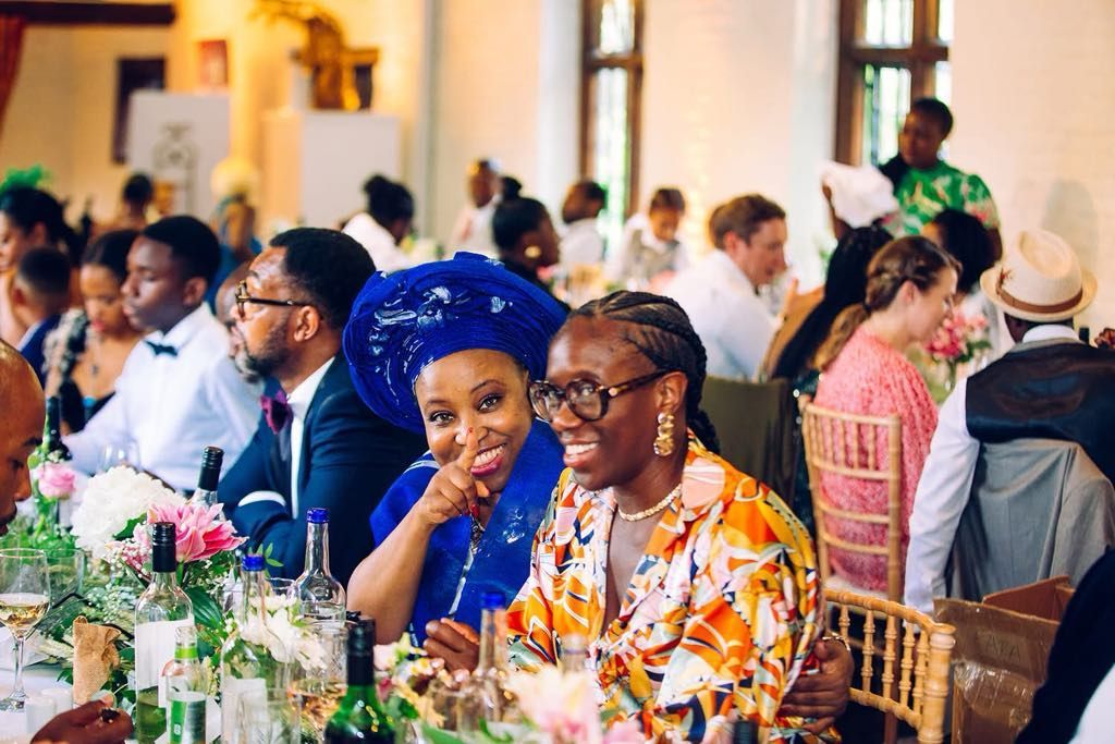 A group of people are sitting at a long table at a wedding reception.
