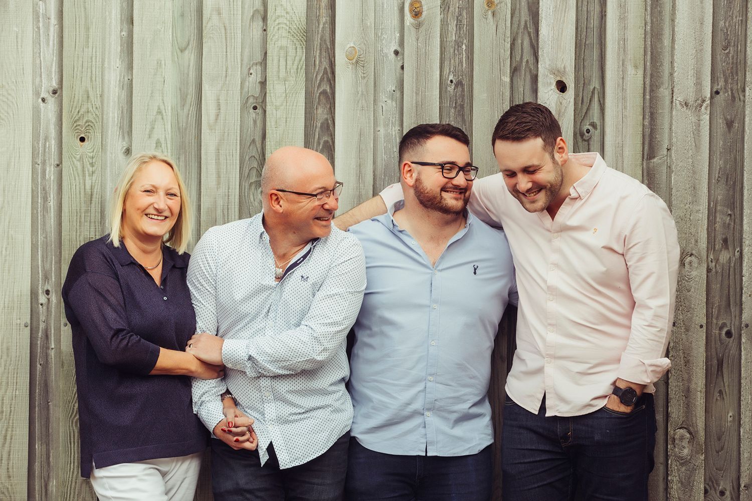 A family is posing for a picture in front of a wooden wall.
