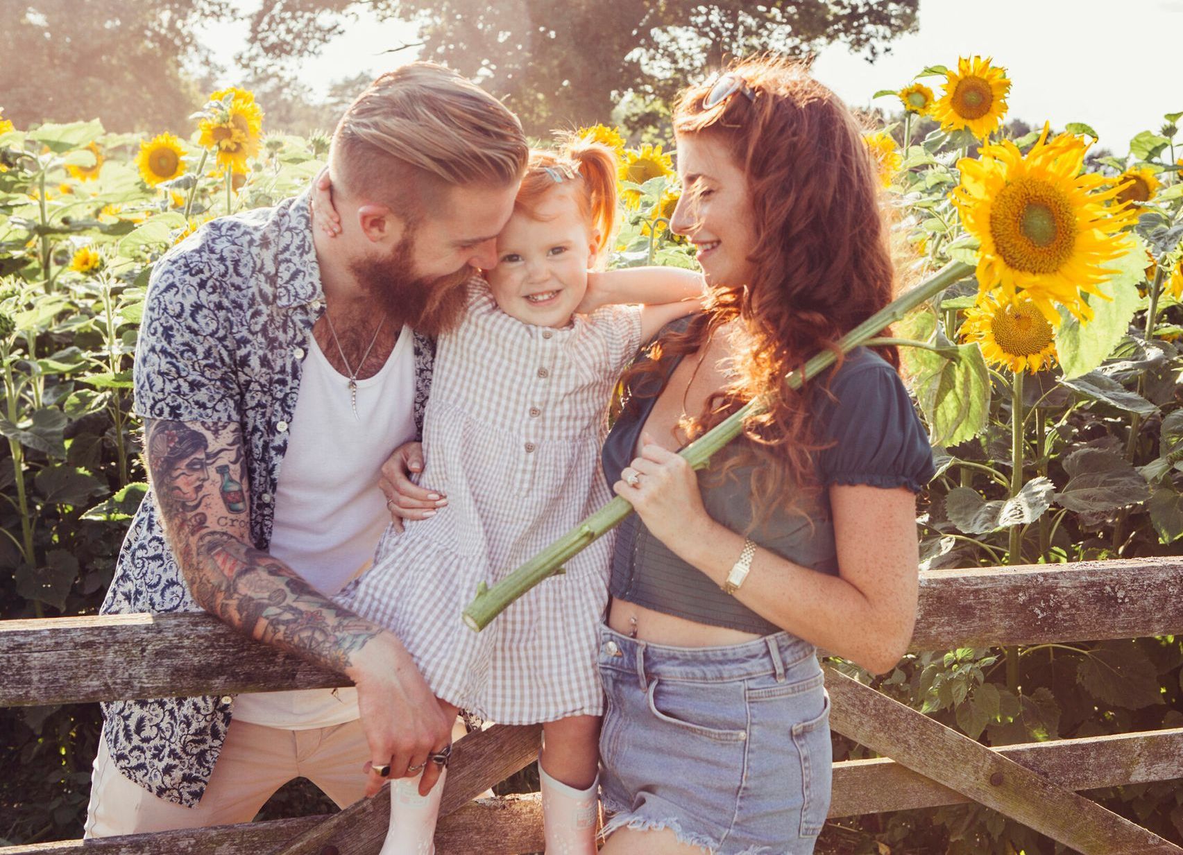 A family is posing for a picture in a field of sunflowers.