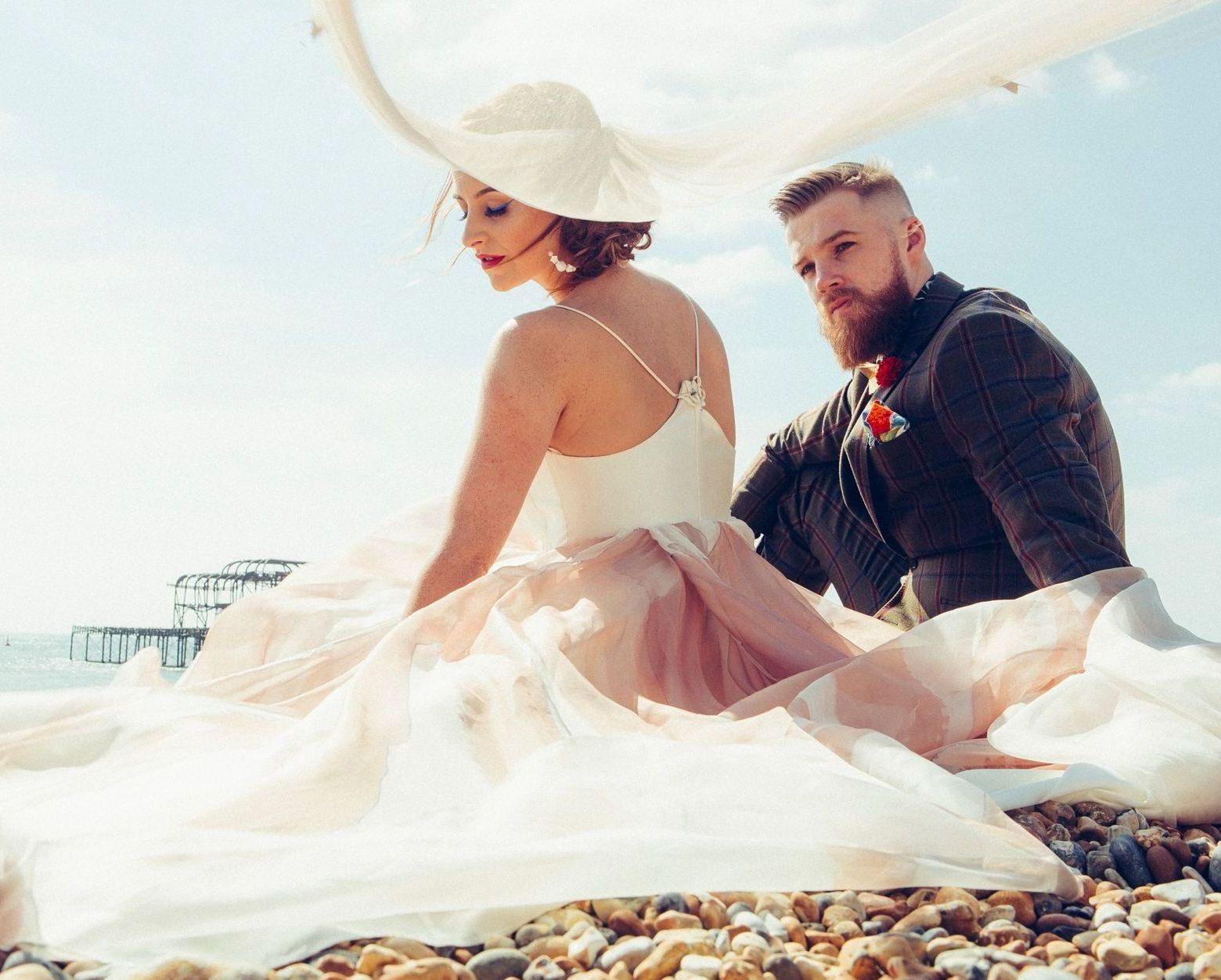 A bride and groom are sitting on a rocky beach.