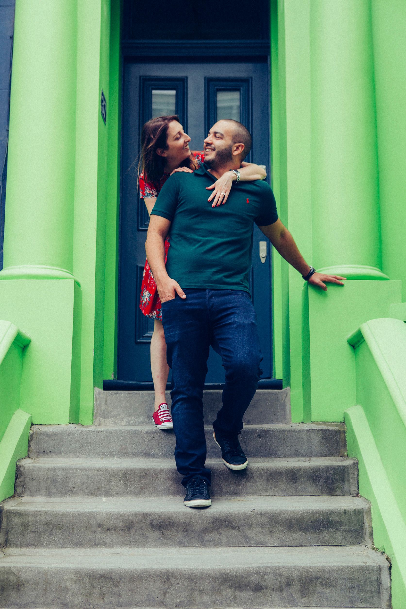 A man and a woman are standing on a set of stairs in front of a green building.