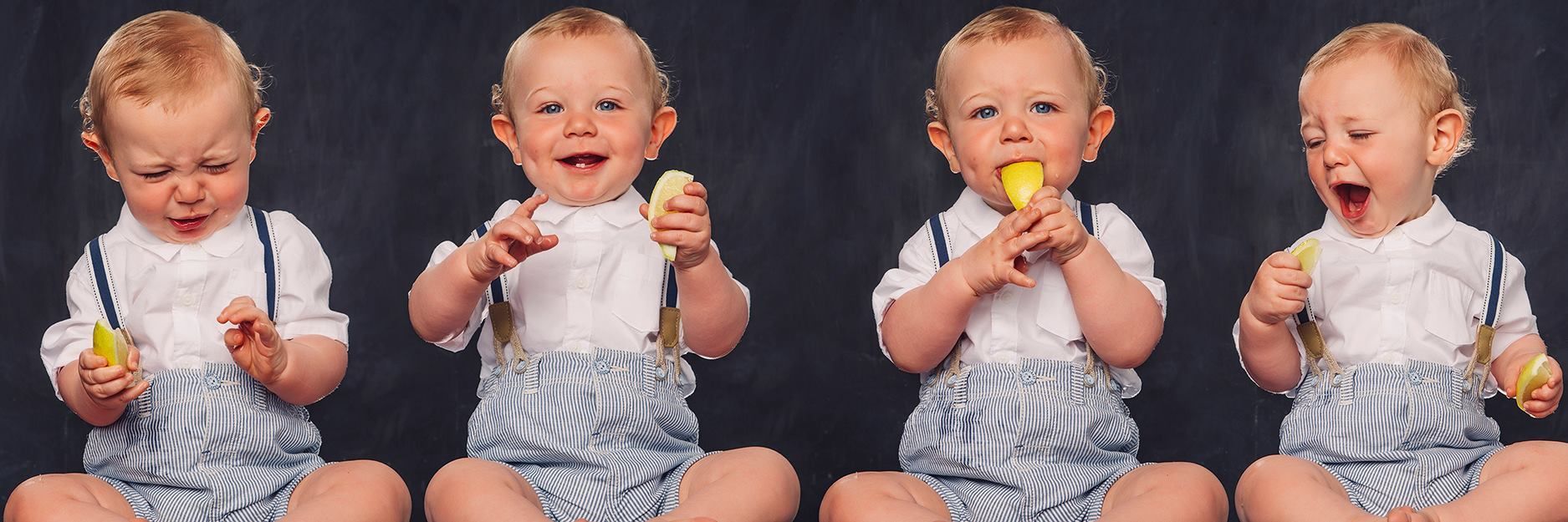 Four babies are sitting next to each other eating lemons