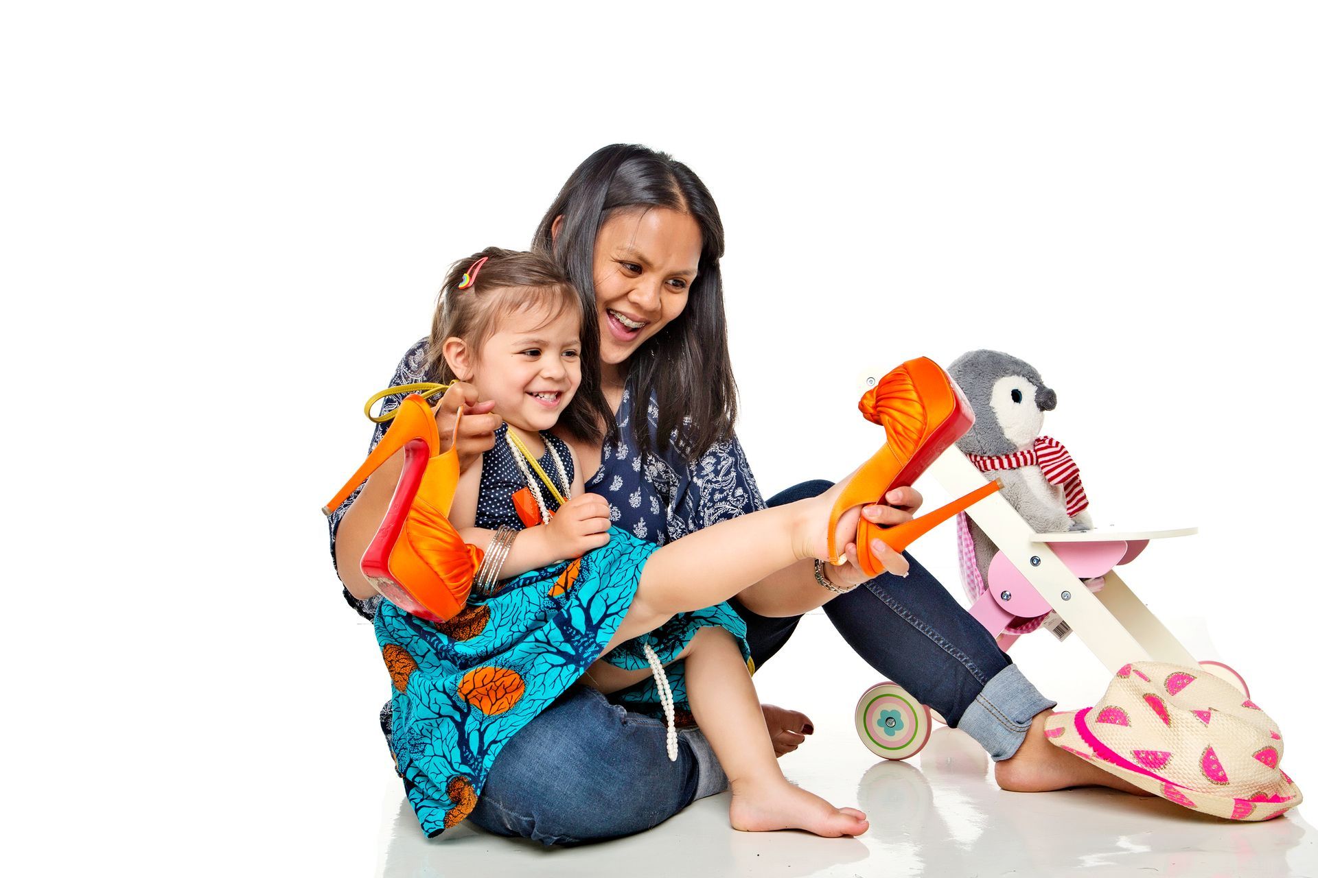 A woman and a little girl are sitting on the floor playing with toys.