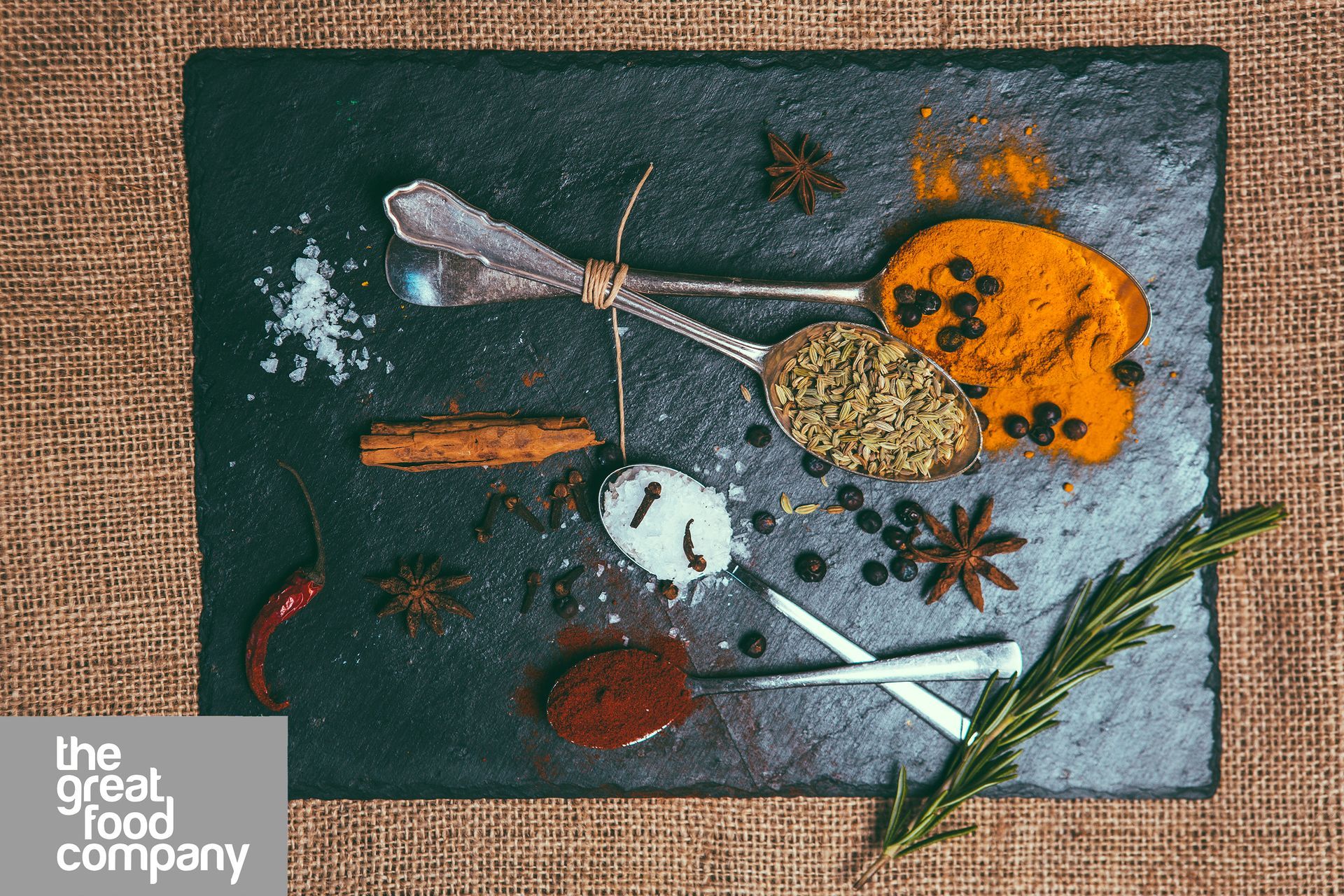 A slate cutting board with spices and spoons on it