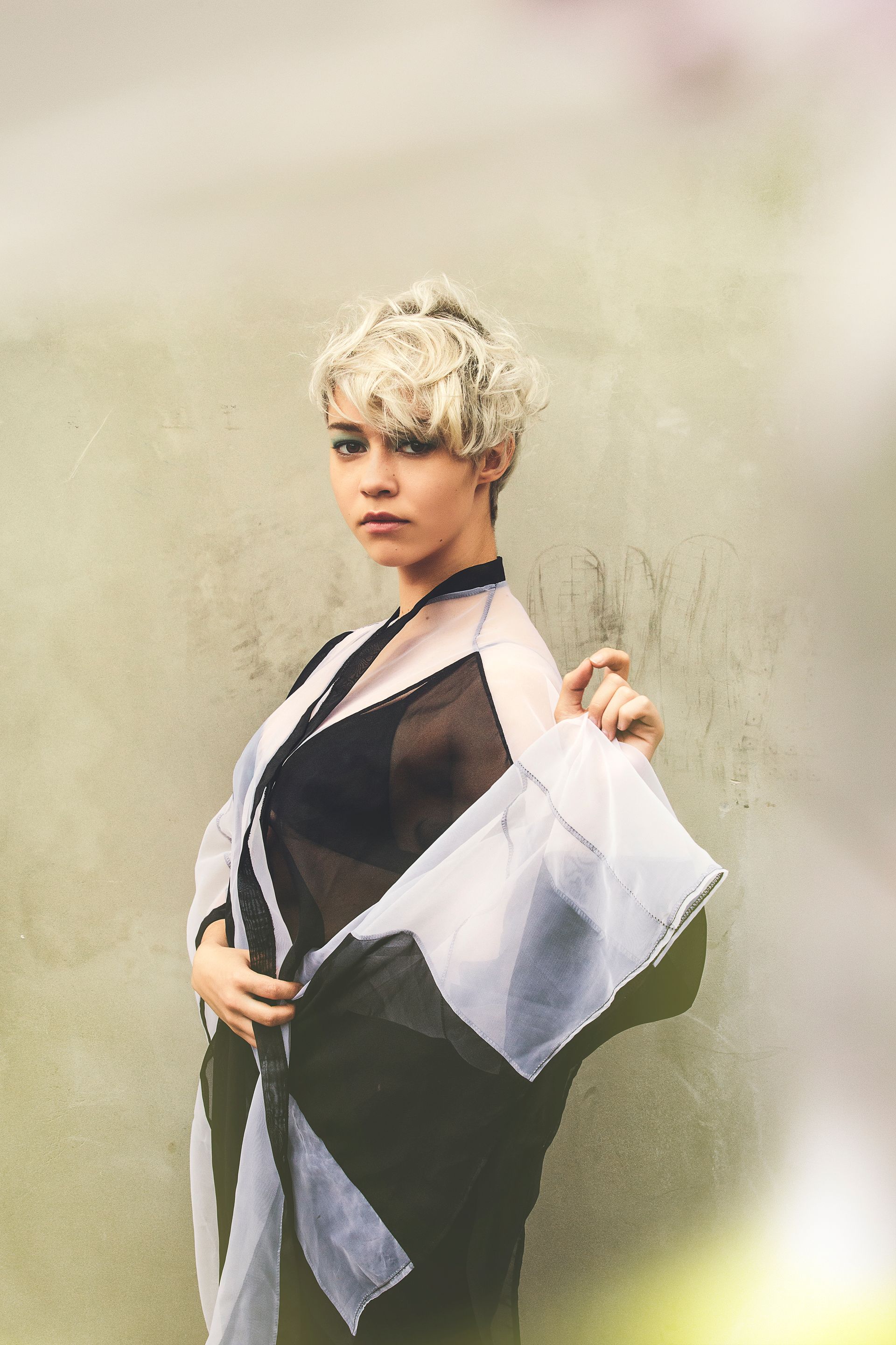 A woman in a black and white dress is standing in front of a wall.