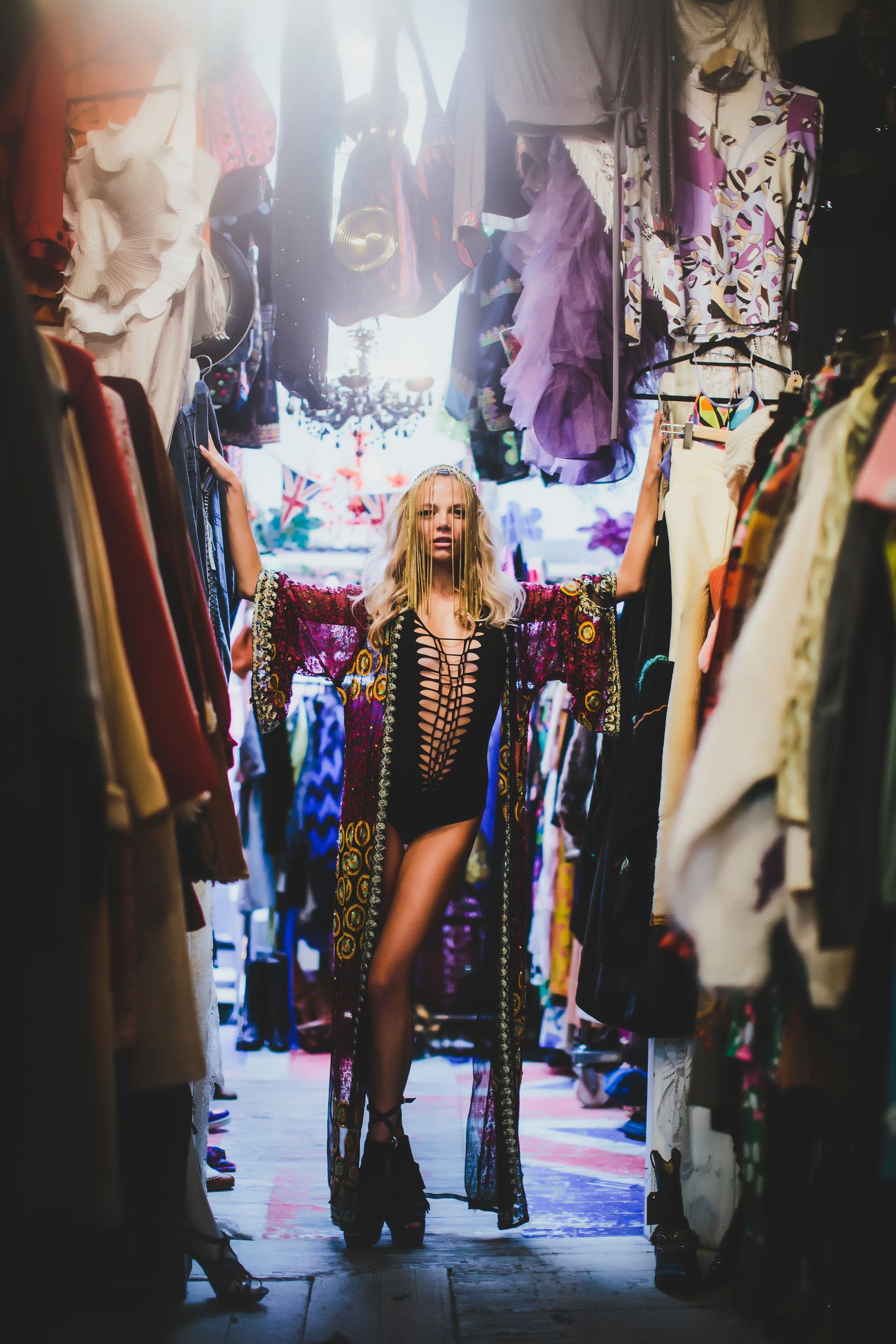 A woman is standing in a room filled with clothes.
