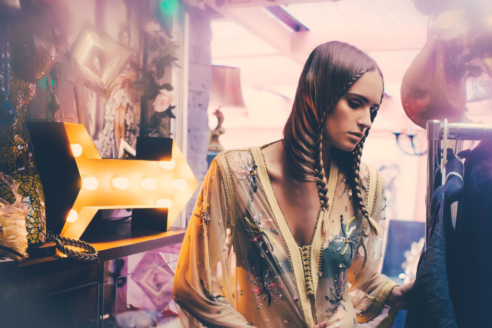 A woman is standing in a room looking at clothes on a rack.