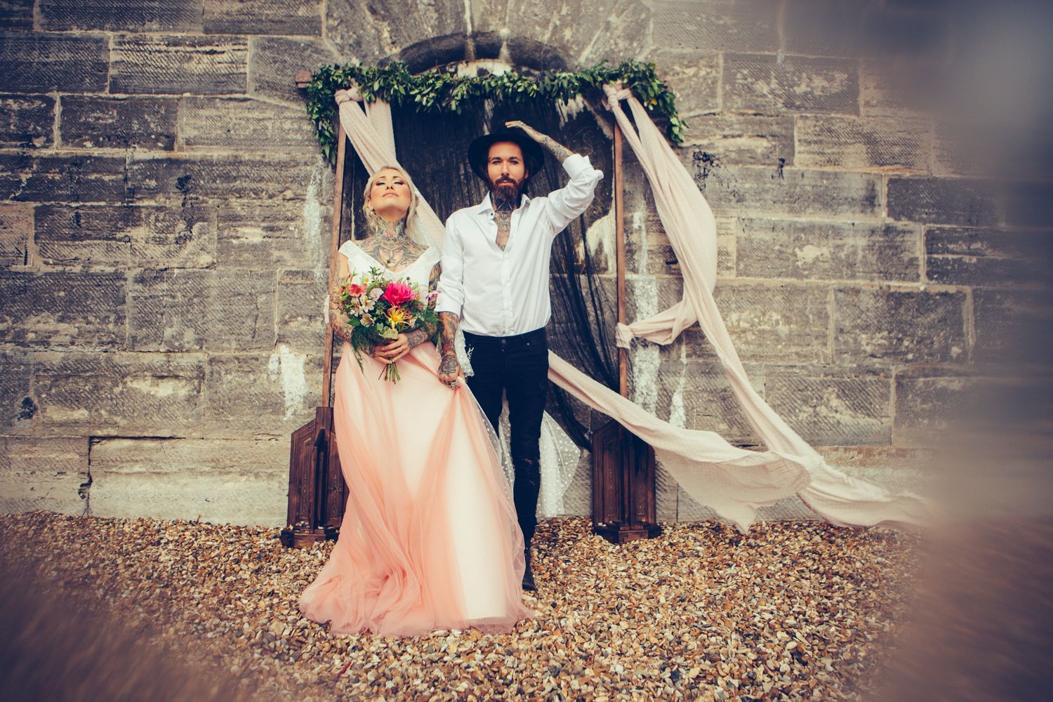 A bride and groom are posing for a picture in front of a brick wall.