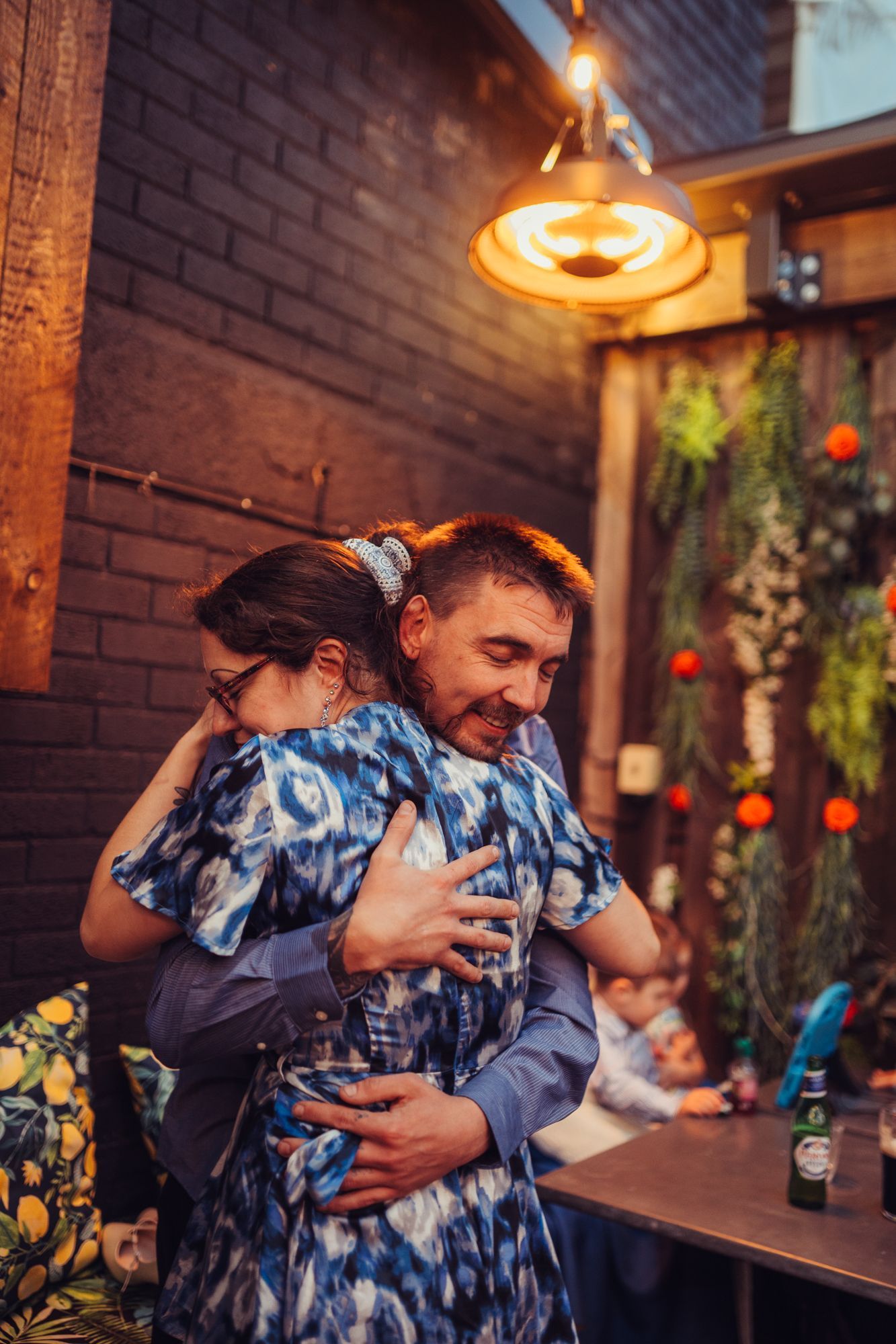 A man and a woman are hugging each other in a restaurant.