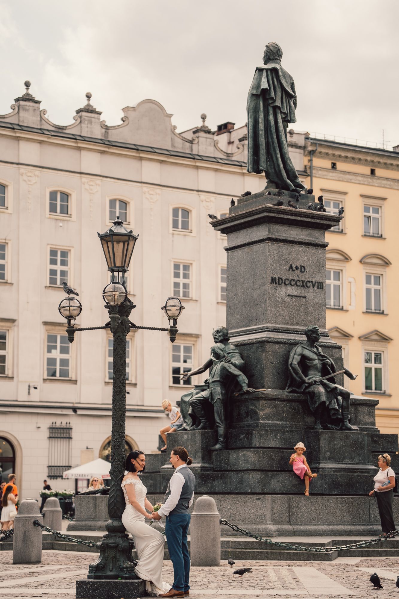A bride and groom are posing for a picture in front of a statue.