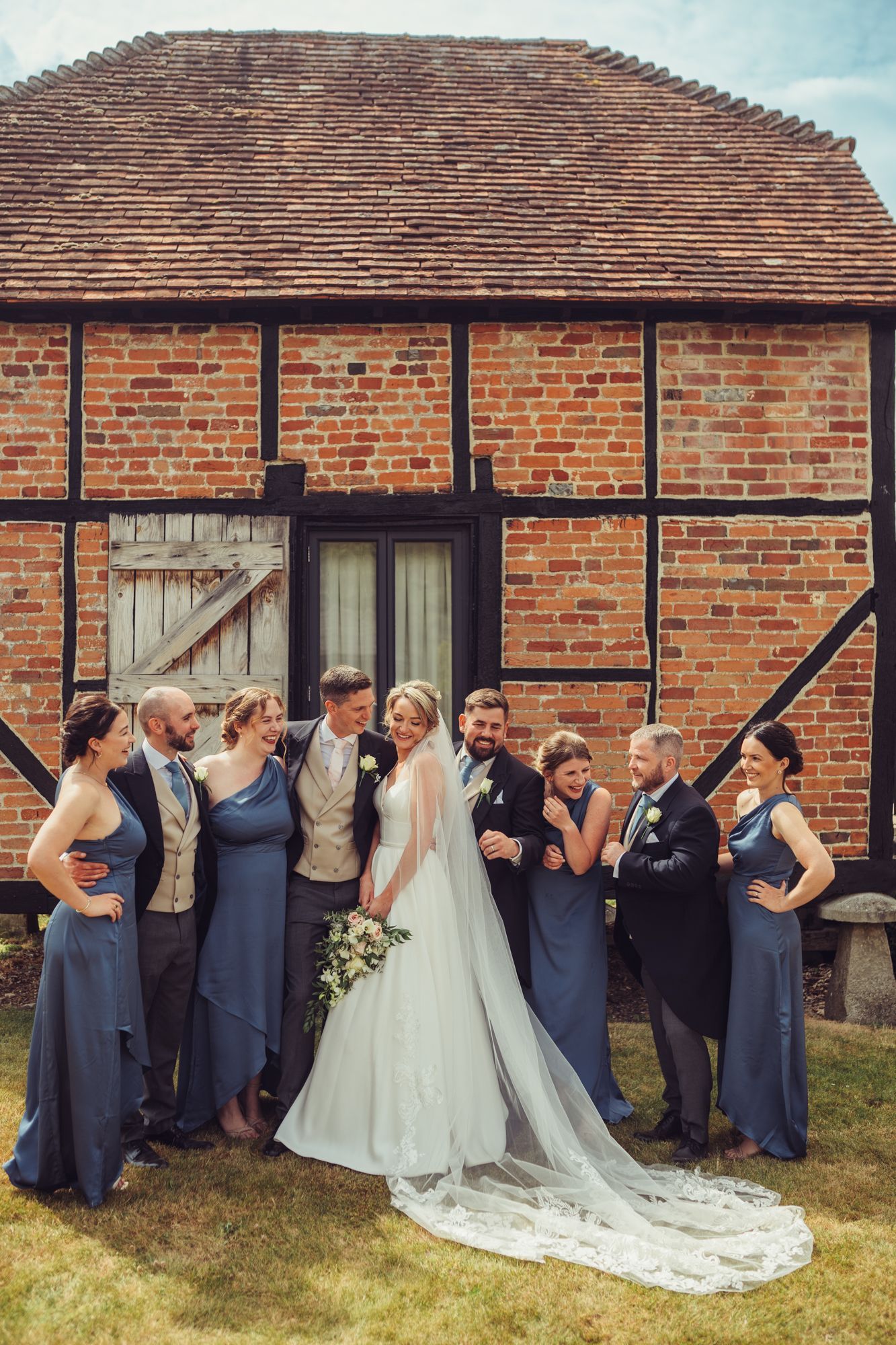 A bride and her wedding party are posing for a picture in front of a brick building.