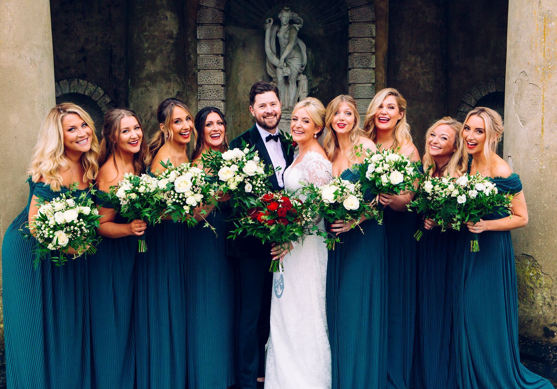A bride and groom are posing for a picture with their bridesmaids.