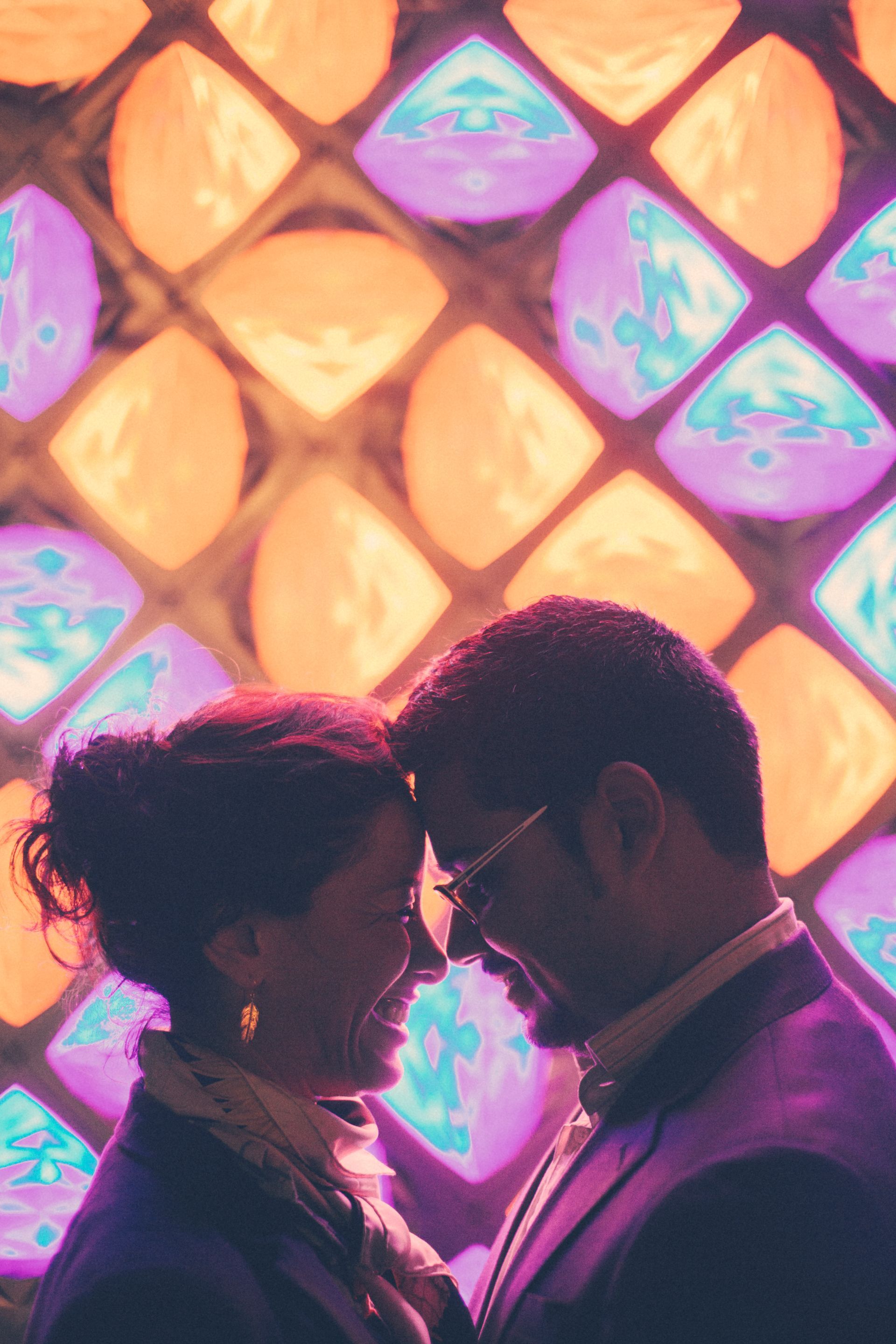 A man and a woman are looking at each other in front of a stained glass window.