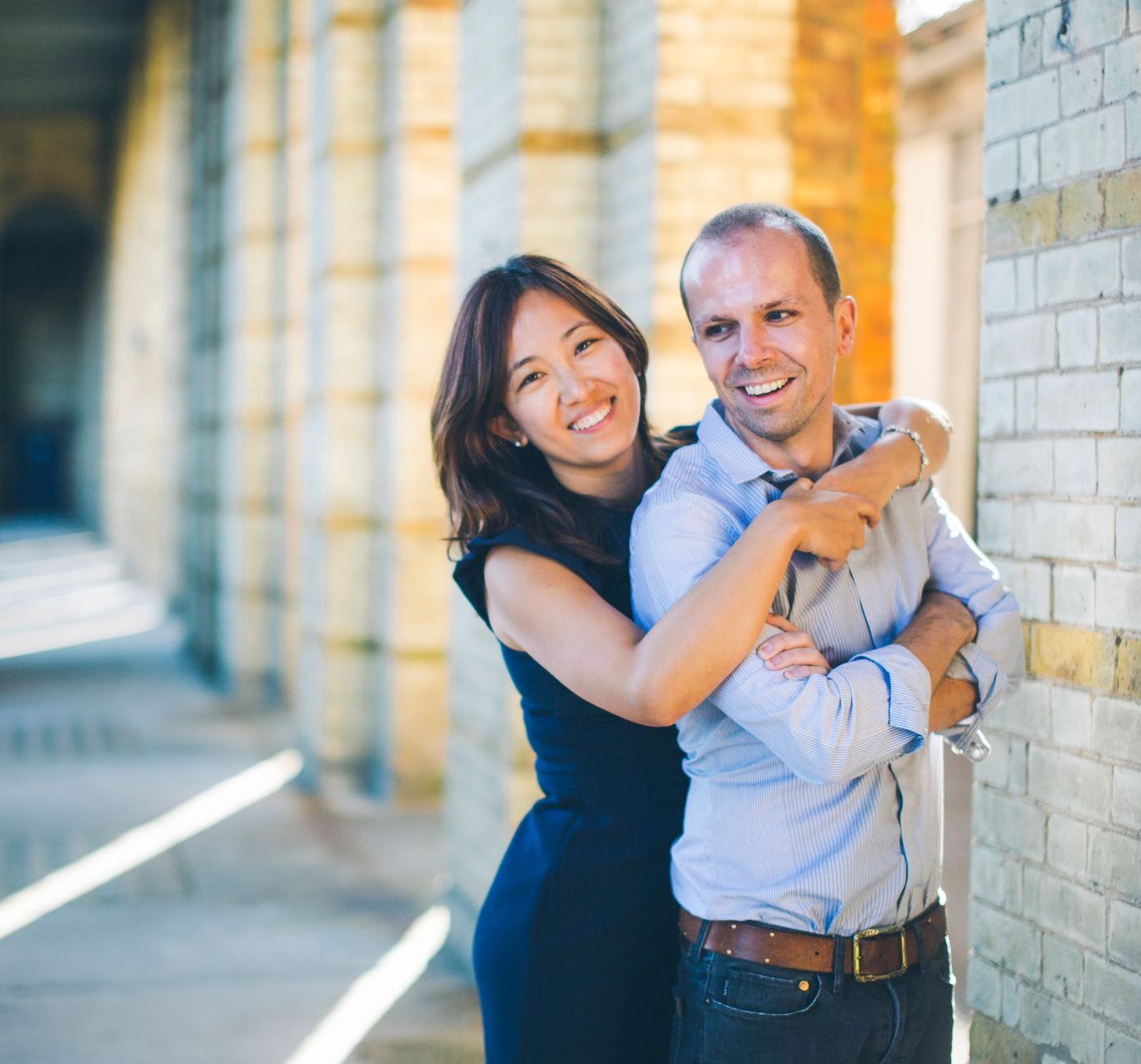 A man and a woman hugging each other in front of a brick wall