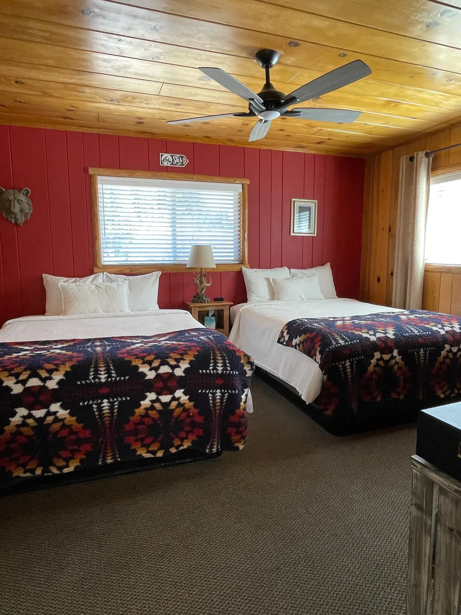 Bedroom with two beds, red walls, wooden ceiling, and a ceiling fan.