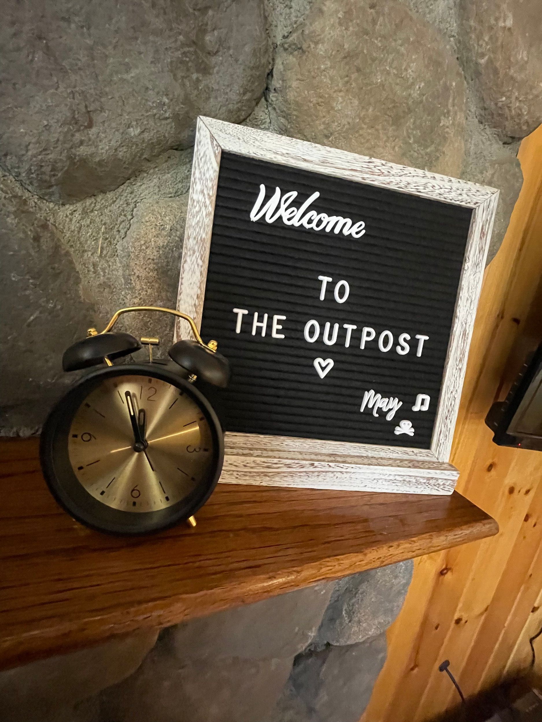 Black alarm clock and framed sign that reads 