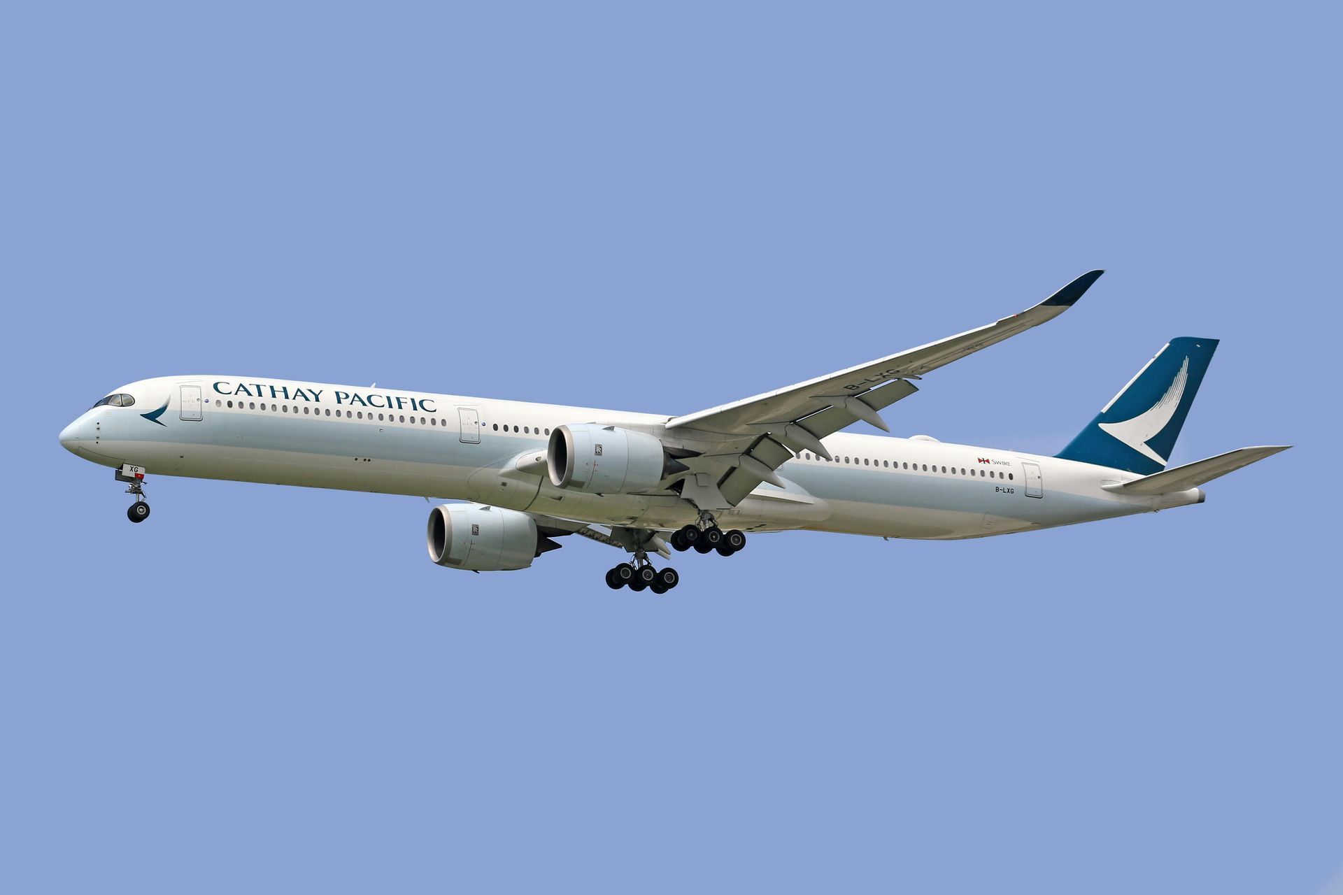 Een Airbus A350 passagiersvliegtuig van Cathay Pacific landt tegen een helderblauwe hemel.