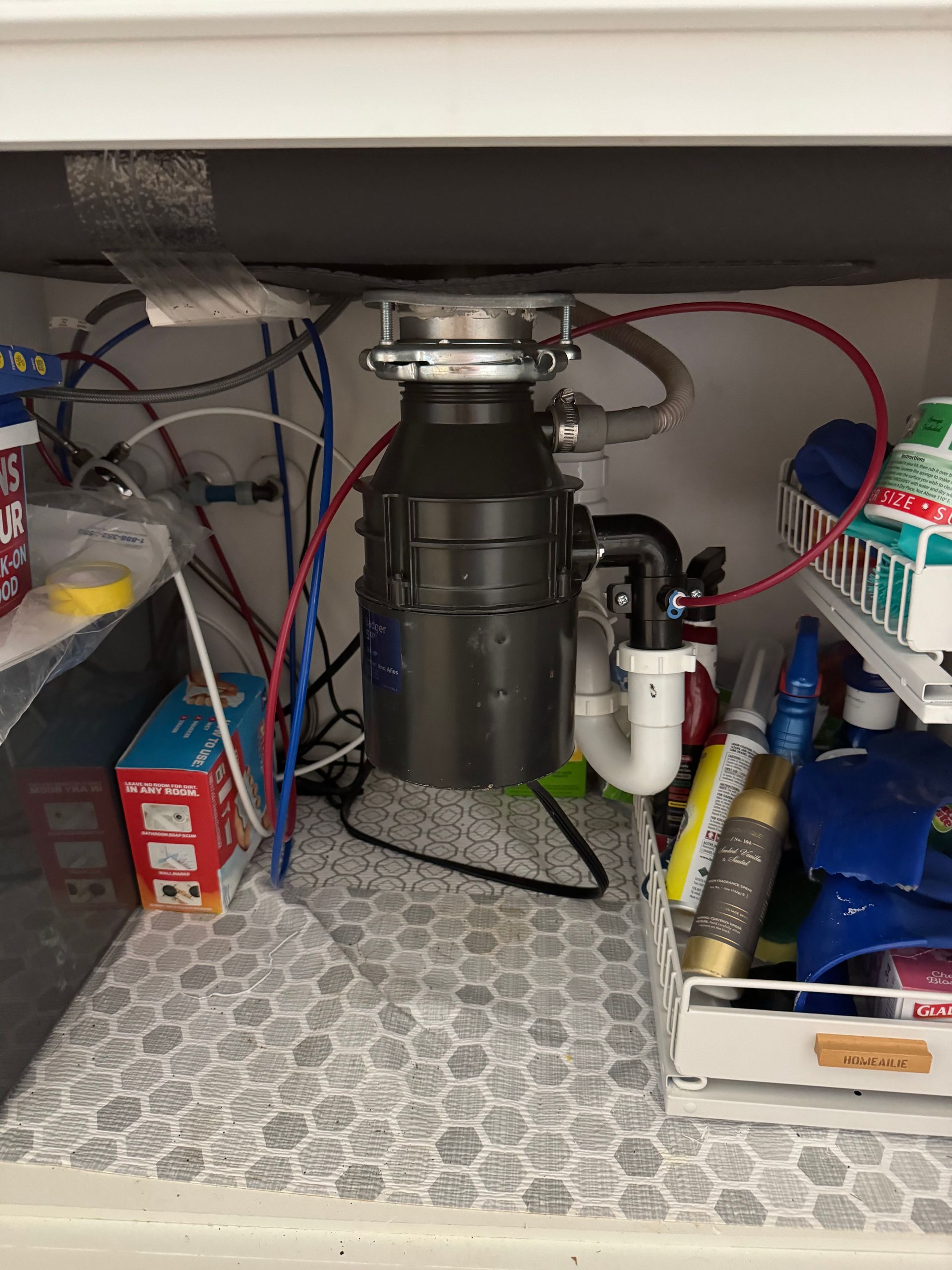 Under-sink cabinet with a garbage disposal, pipes, wires, and cleaning supplies
