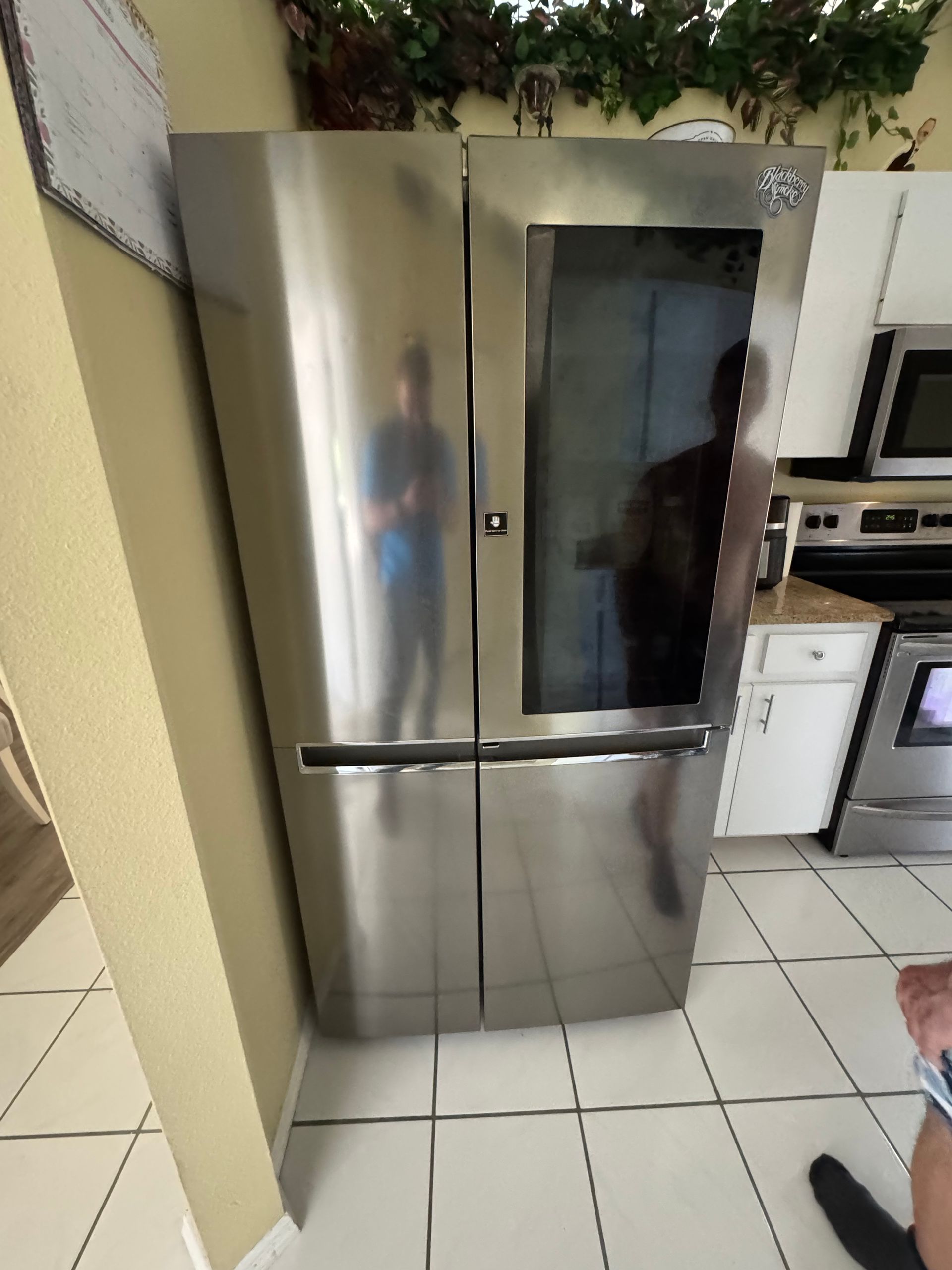 Stainless steel refrigerator in a kitchen with white tile floor and cabinets nearby