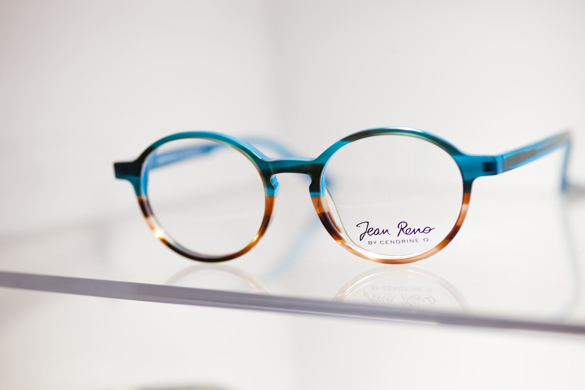 Une paire de lunettes posée sur une étagère en verre.
