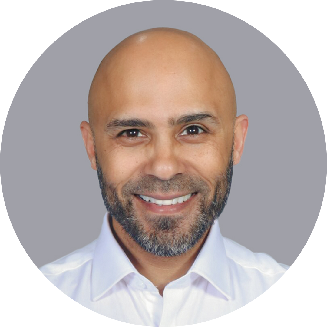Smiling bald man with a salt-and-pepper beard in a white shirt on a gray background