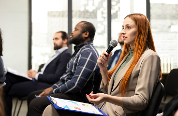 Panel discussion with a woman speaking into a microphone while seated among attentive audience members