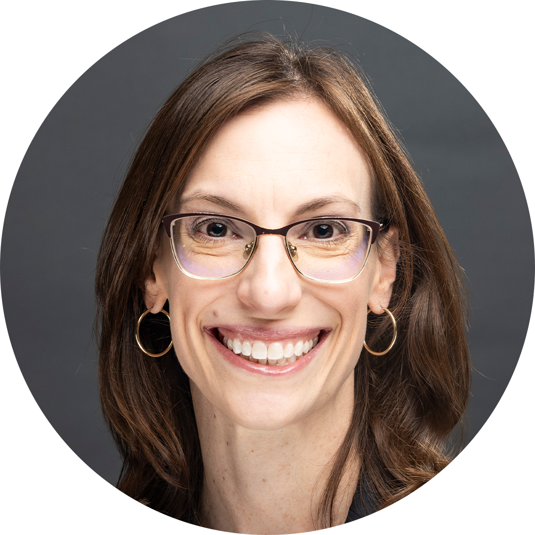 Smiling woman with glasses against a dark gray background