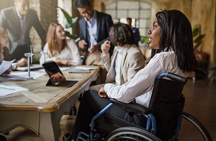 Team meeting in a conference room, with a woman in a wheelchair in the foreground.