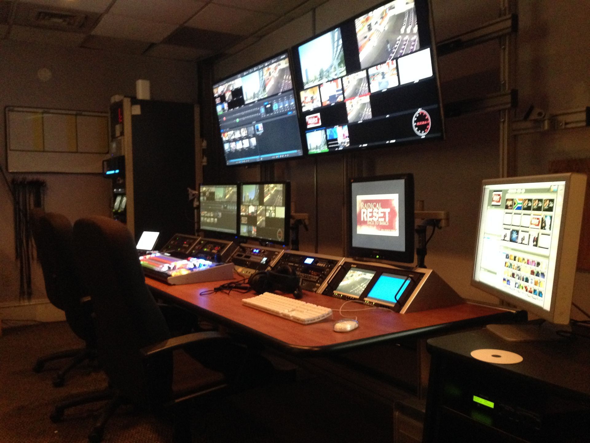 Control room with multiple monitors displaying video feeds and editing interfaces.